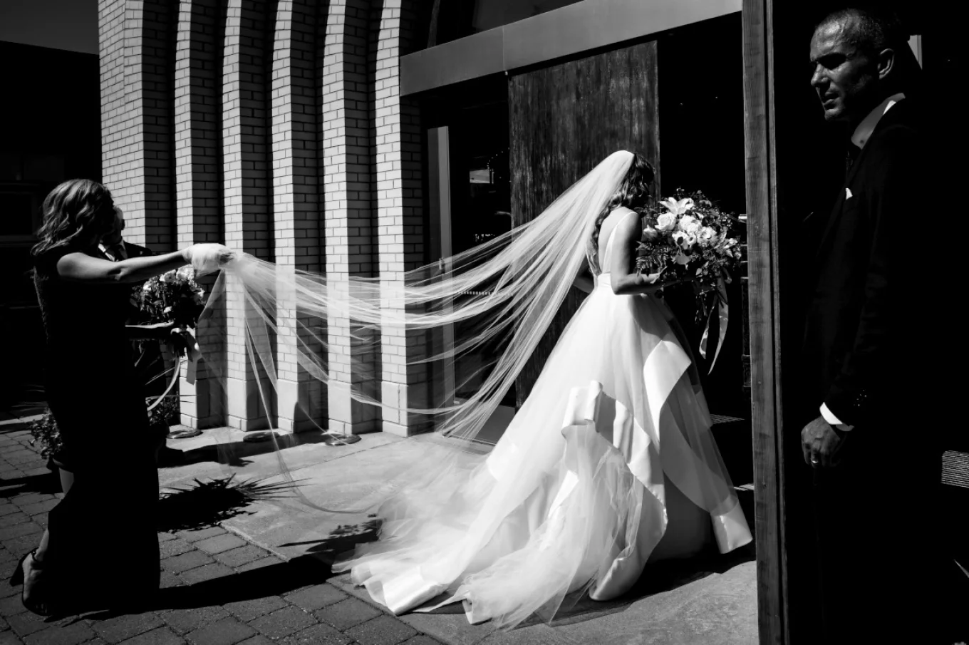 The Bride entering a church. Bridesmaids are holding her vail.