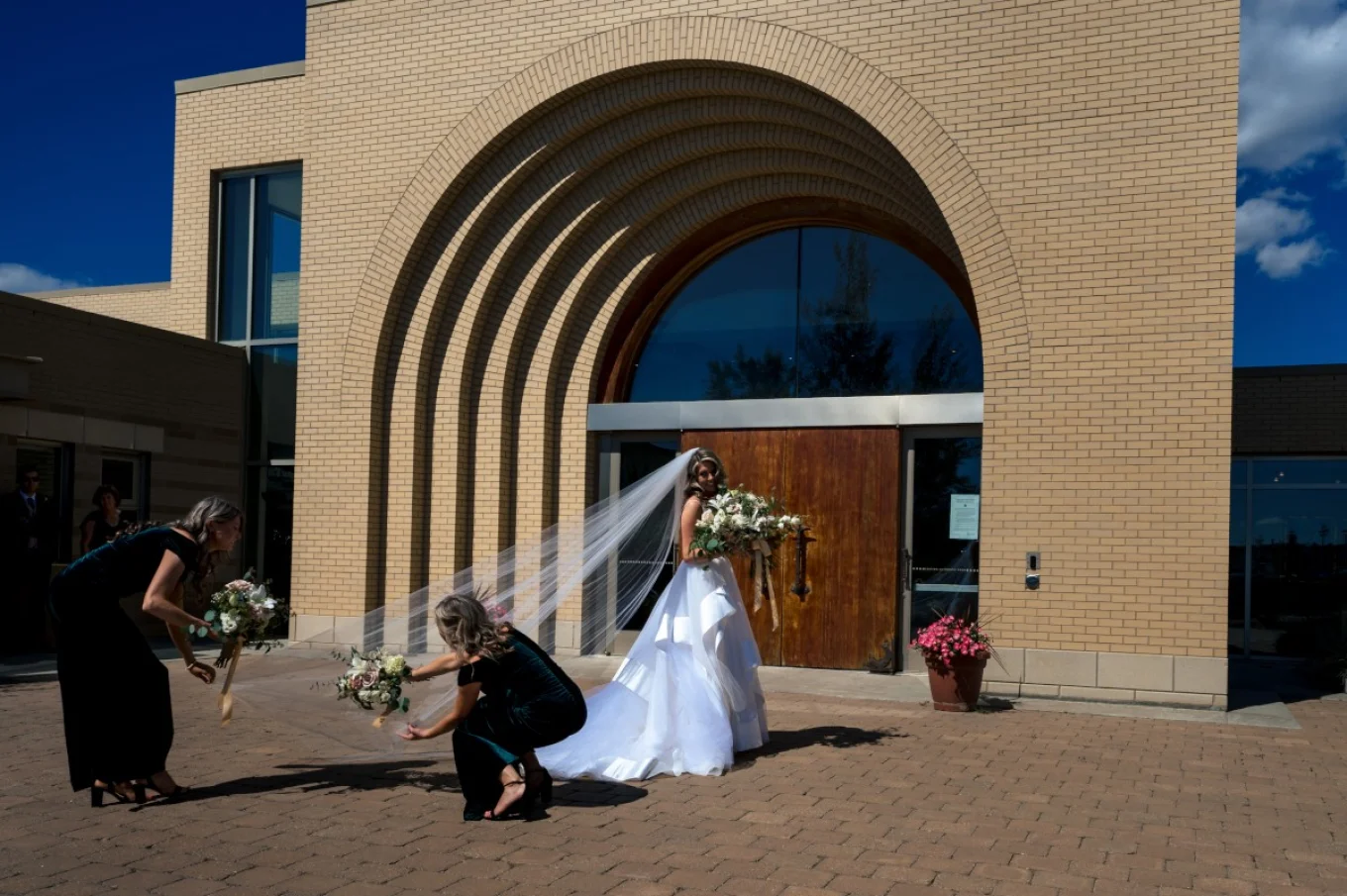 Bridesmaids are helping with the bride's vial in front of the church in Calgary.