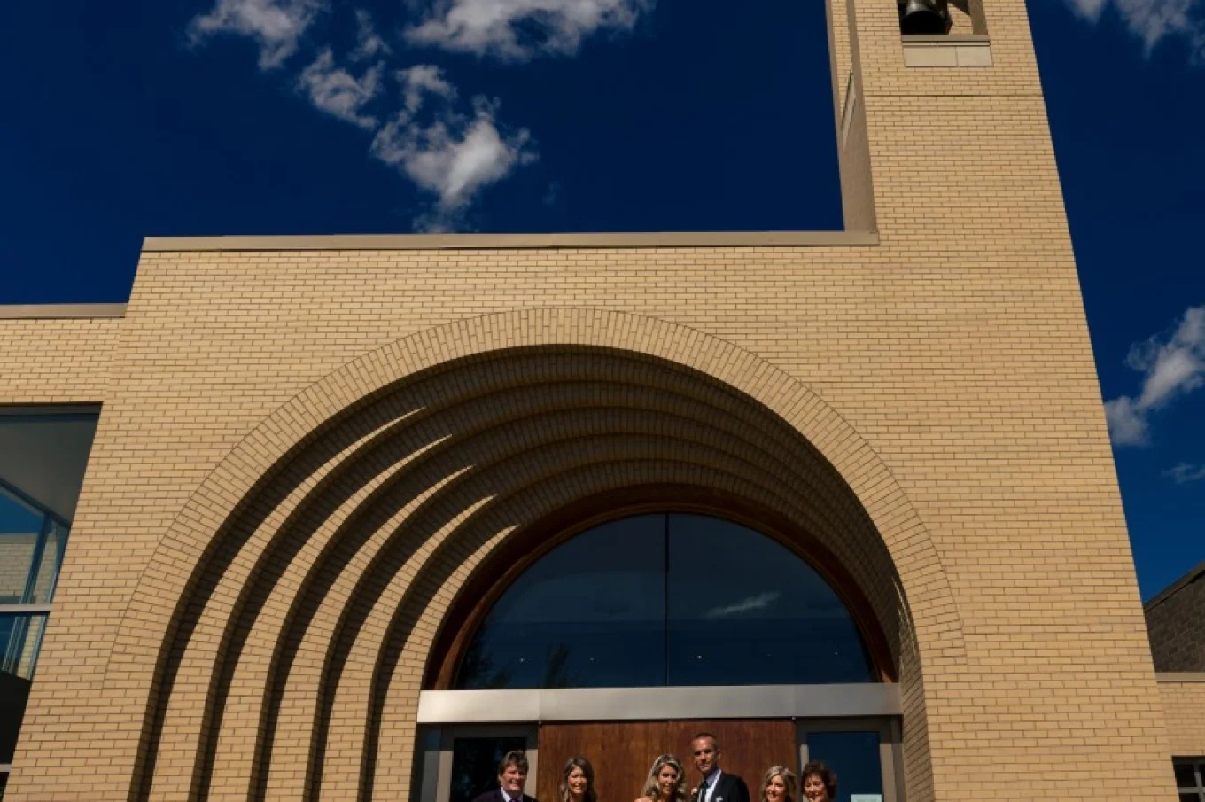 A group of the wedding quests with newlyweds are posing to Calgary Wedding Photographer in front of the church .