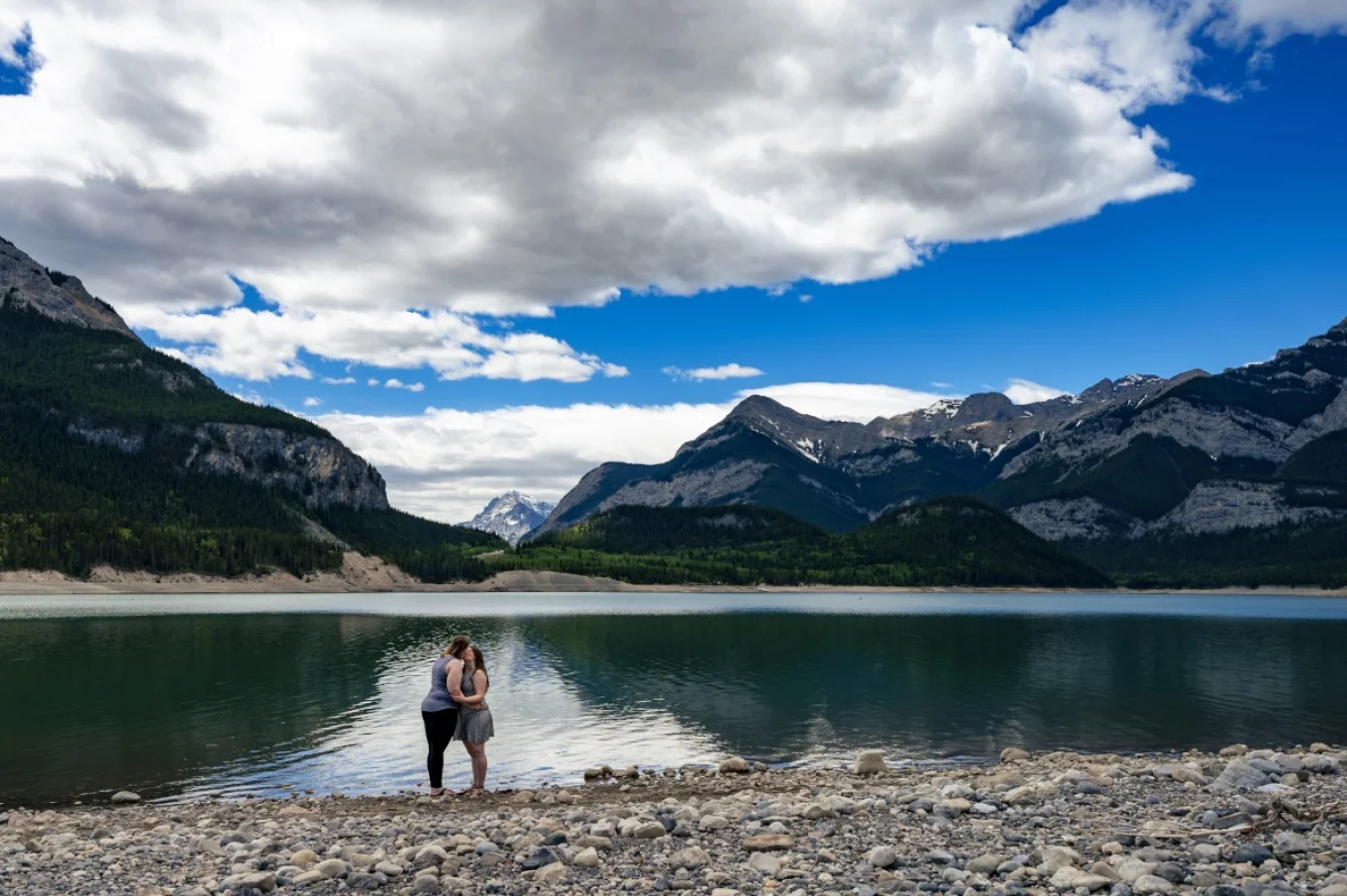 Same sex couple romantic kiss at Bow Lake. They Are surrounded by the Canadian Rockies.