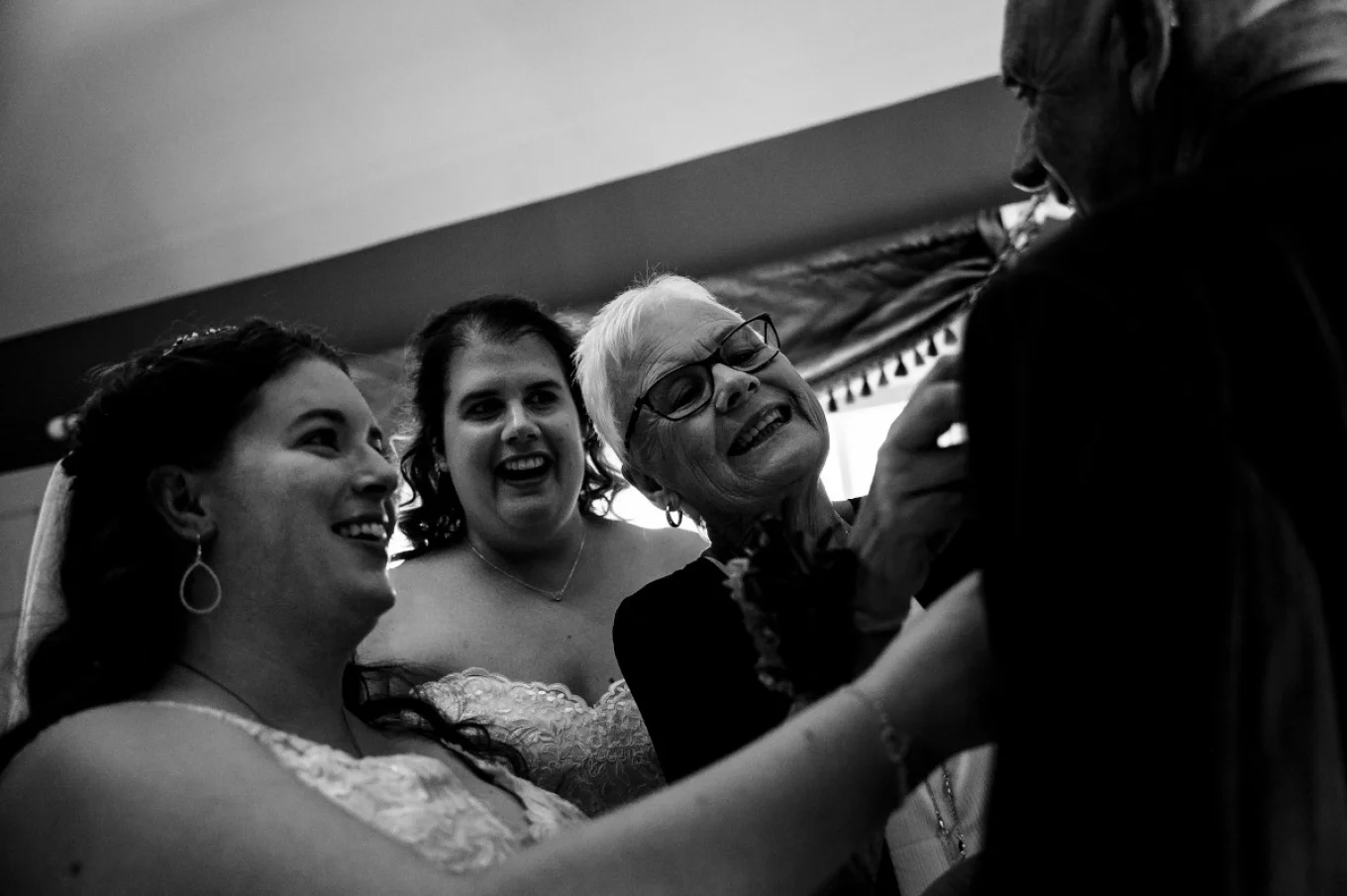 Brides are helping their father to put on a tie before Calgary Wedding Ceremony.