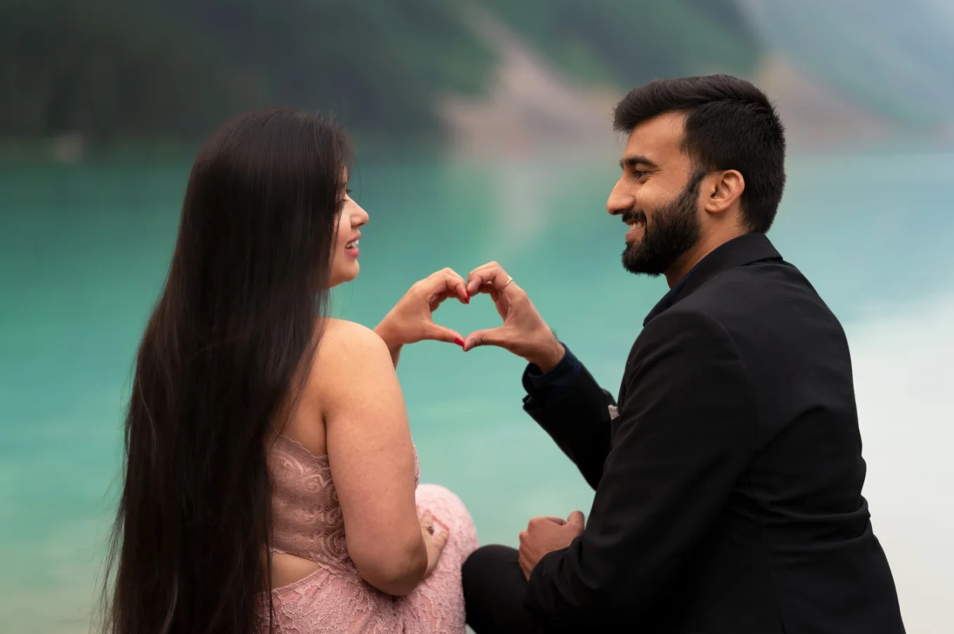 Couple in love look at each other and creates a hart with their hands.