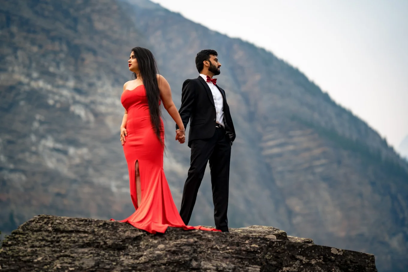 Couple of lovers holds their hands and look at majestic Canadian Rockies.