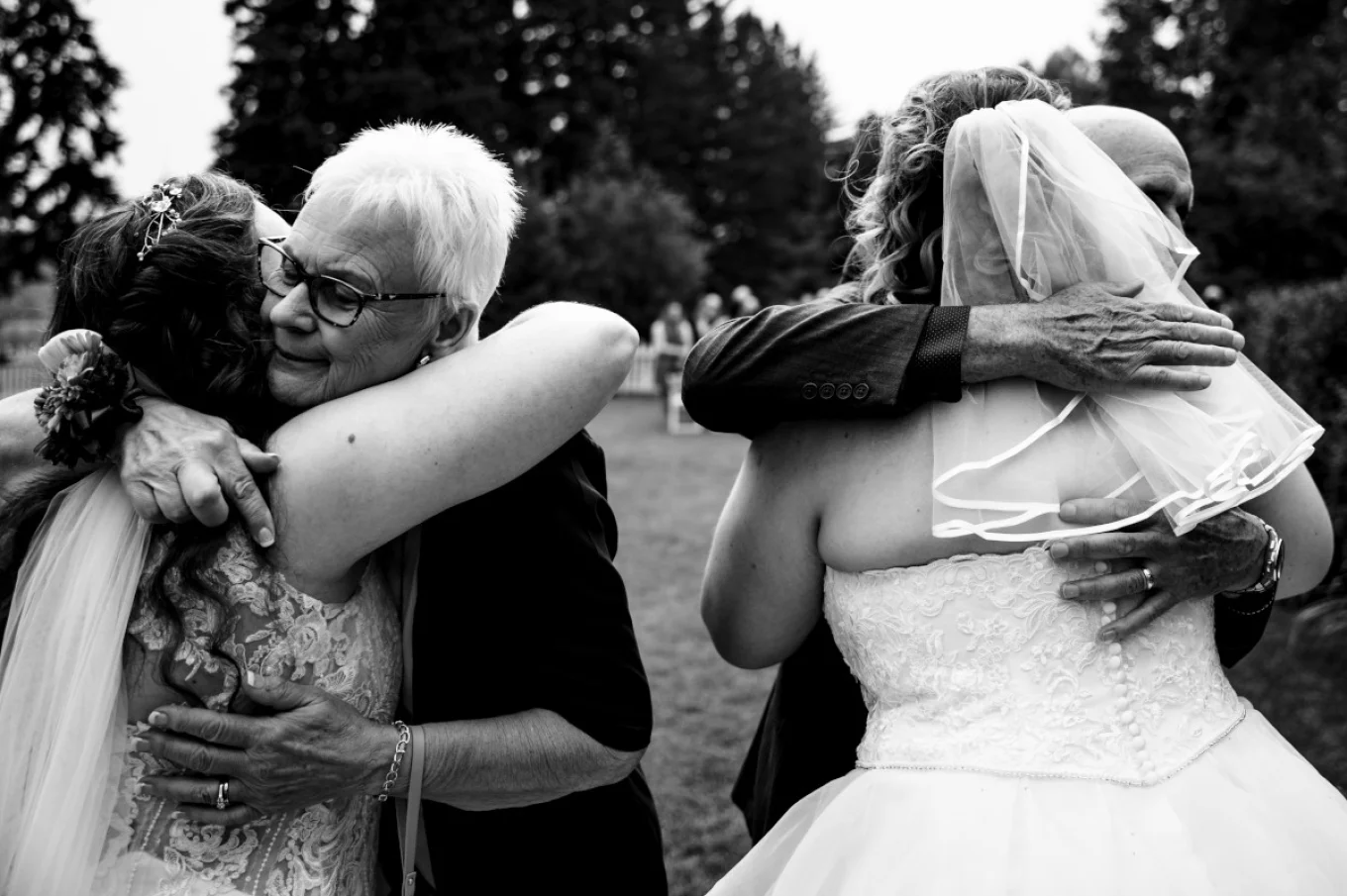 Parents of the newlyweds are hugging the brides.