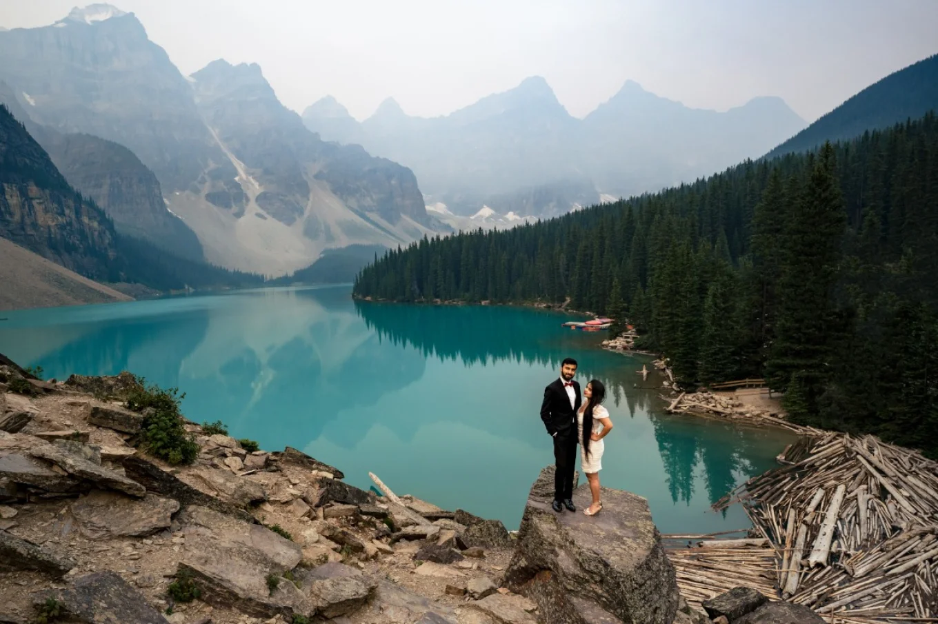 Dressed couple standing at the huge rock at Moraine Lake. They are happily dancing. e