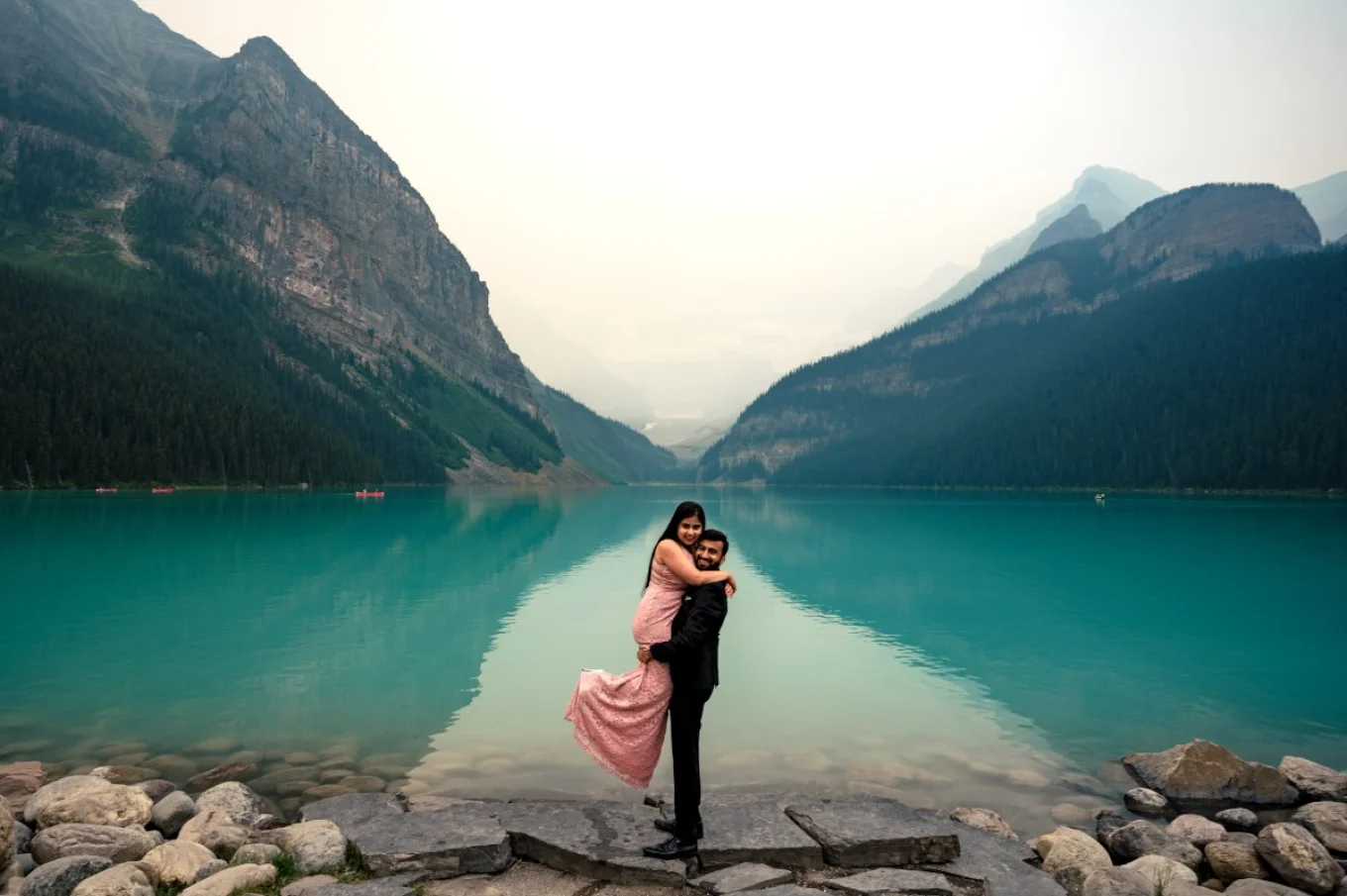 A man lifts his fiancee and they both look at Banff Weeding Photographer at Lake Louise
