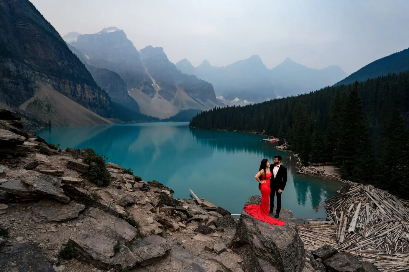 Engagement session at Moraine Lake in Banff. The couple standing on a giant rock. They are surrounded by the Canadian Rockies and turquoise lake