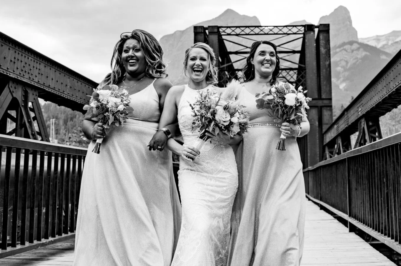 bride and bride maids walking and laughing on the bridge in Canmore.