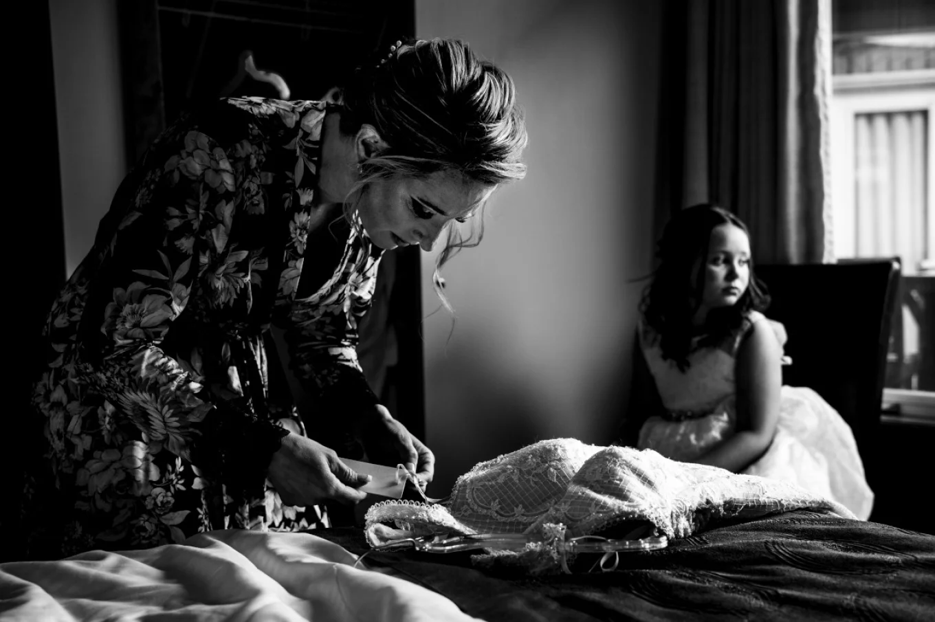 Bride is checking a wedding dress and flower girl is looking through the window.