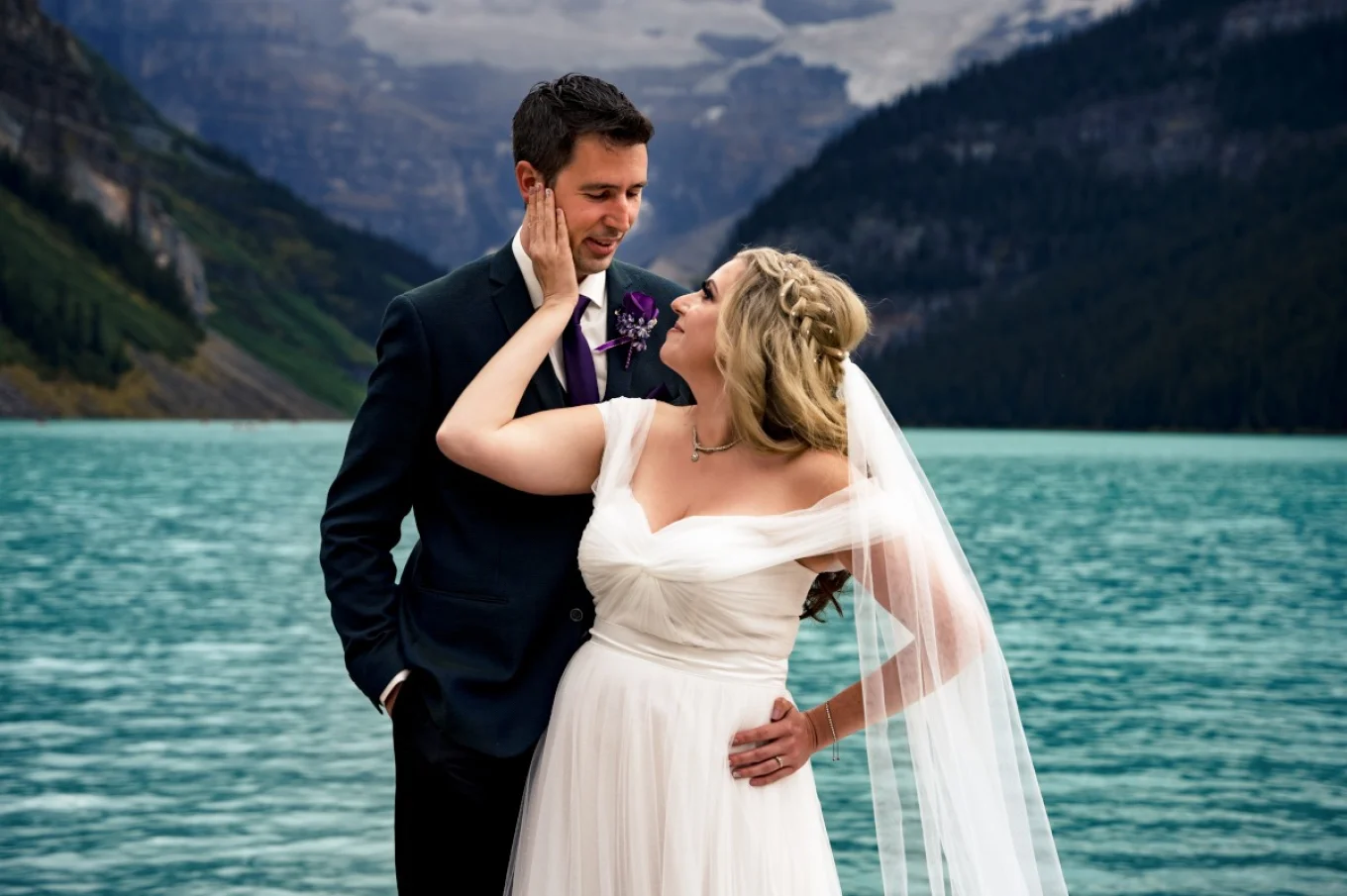 Bride puts her hand on the grooms cheek. They smile to each other.