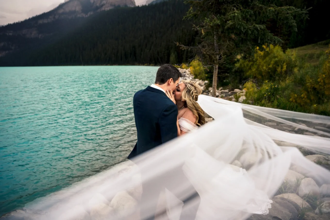 Newlyweds kiss under the veil.