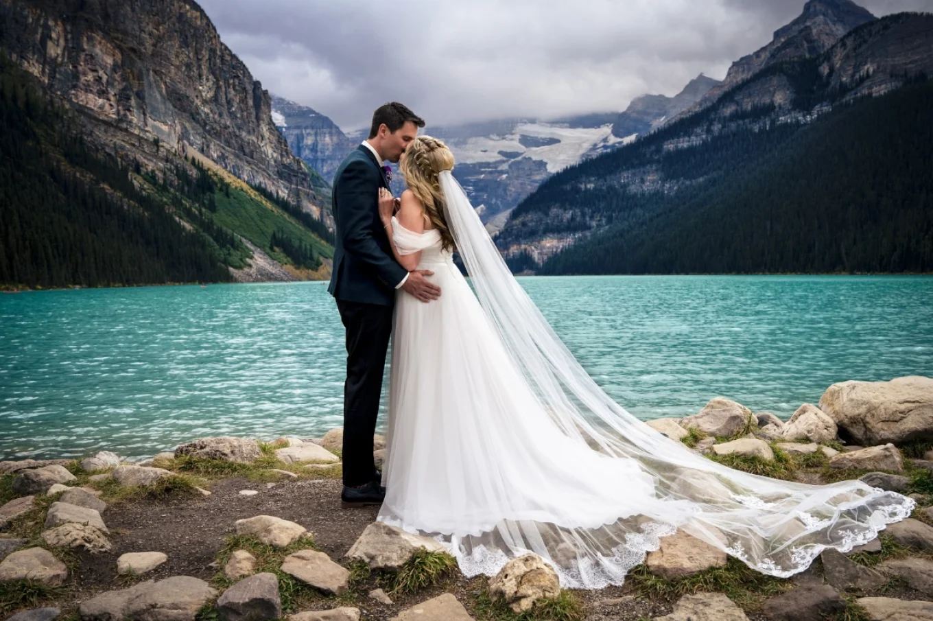 Banff Wedding Photography at Lake Louise. Newlyweds kiss at the lake.