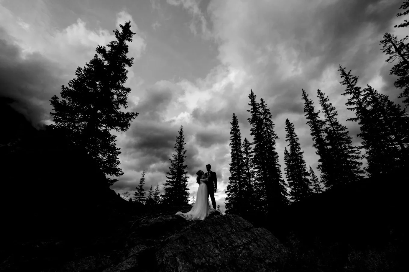 Banff Wedding Photography in dark and moody style. Newlyweds look at each other in the Canadian Rockies.