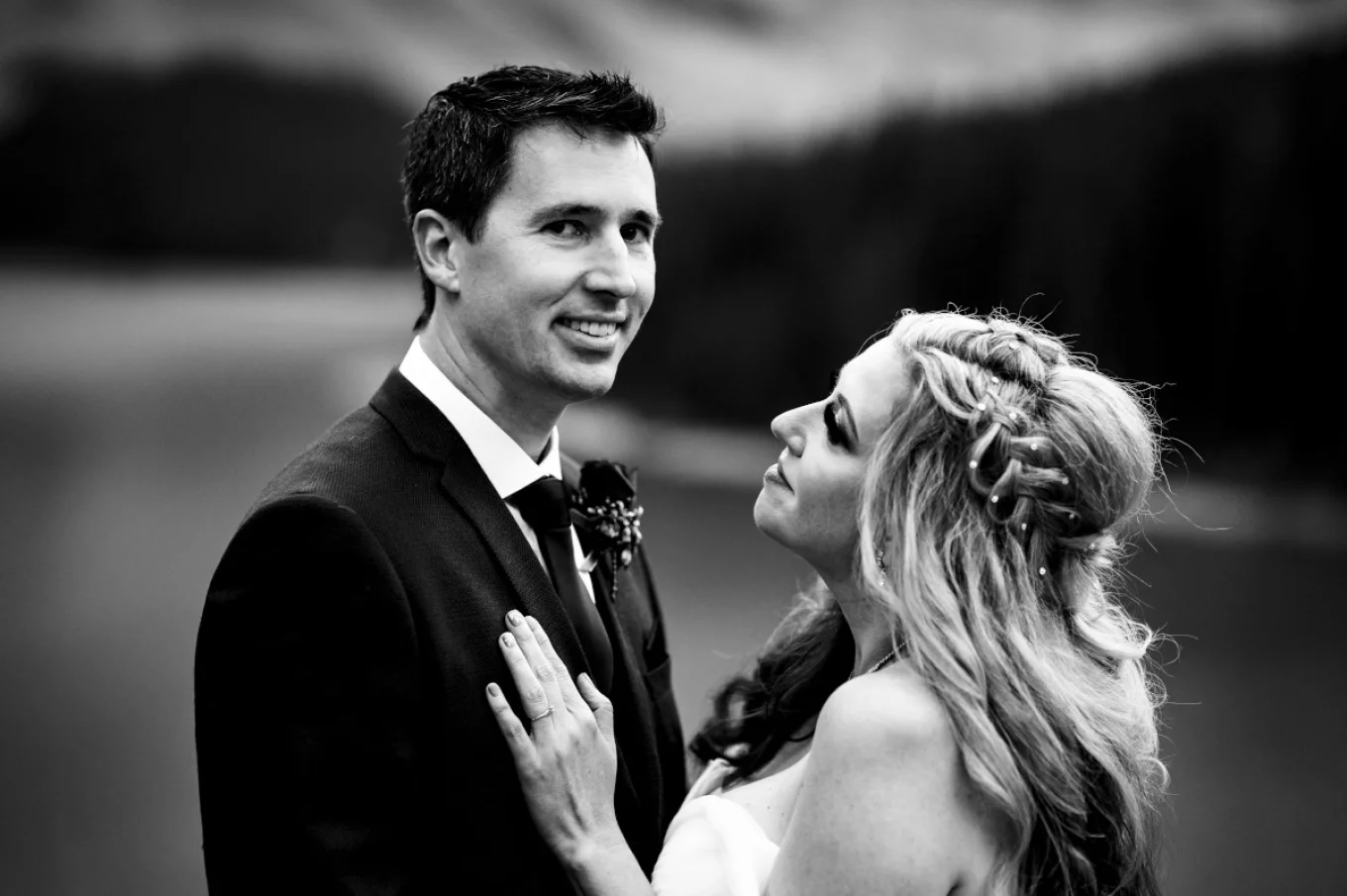 Newlyweds portrait in black and white. Bride looks at the groom with love. Groom looks at the Banff Wedding Photographer camera.