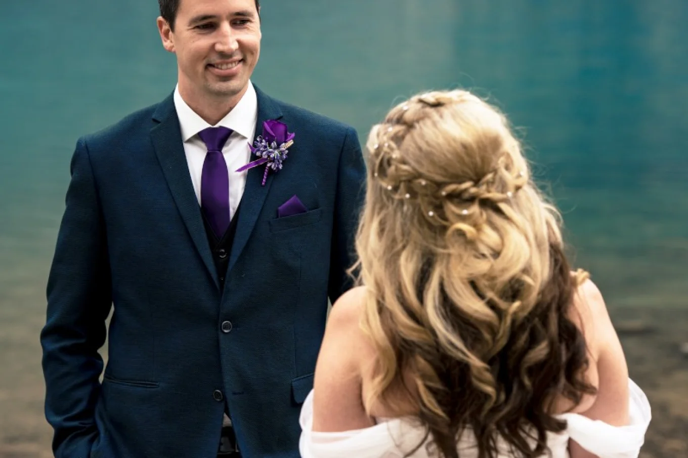Groom admire beauty of his wife at Moraine Lake. He smiles to her.