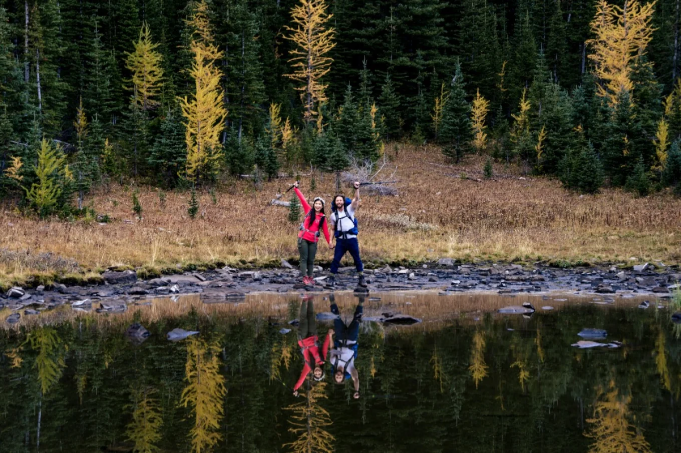 Hikers on their way lifting their equipment and smile to camera.