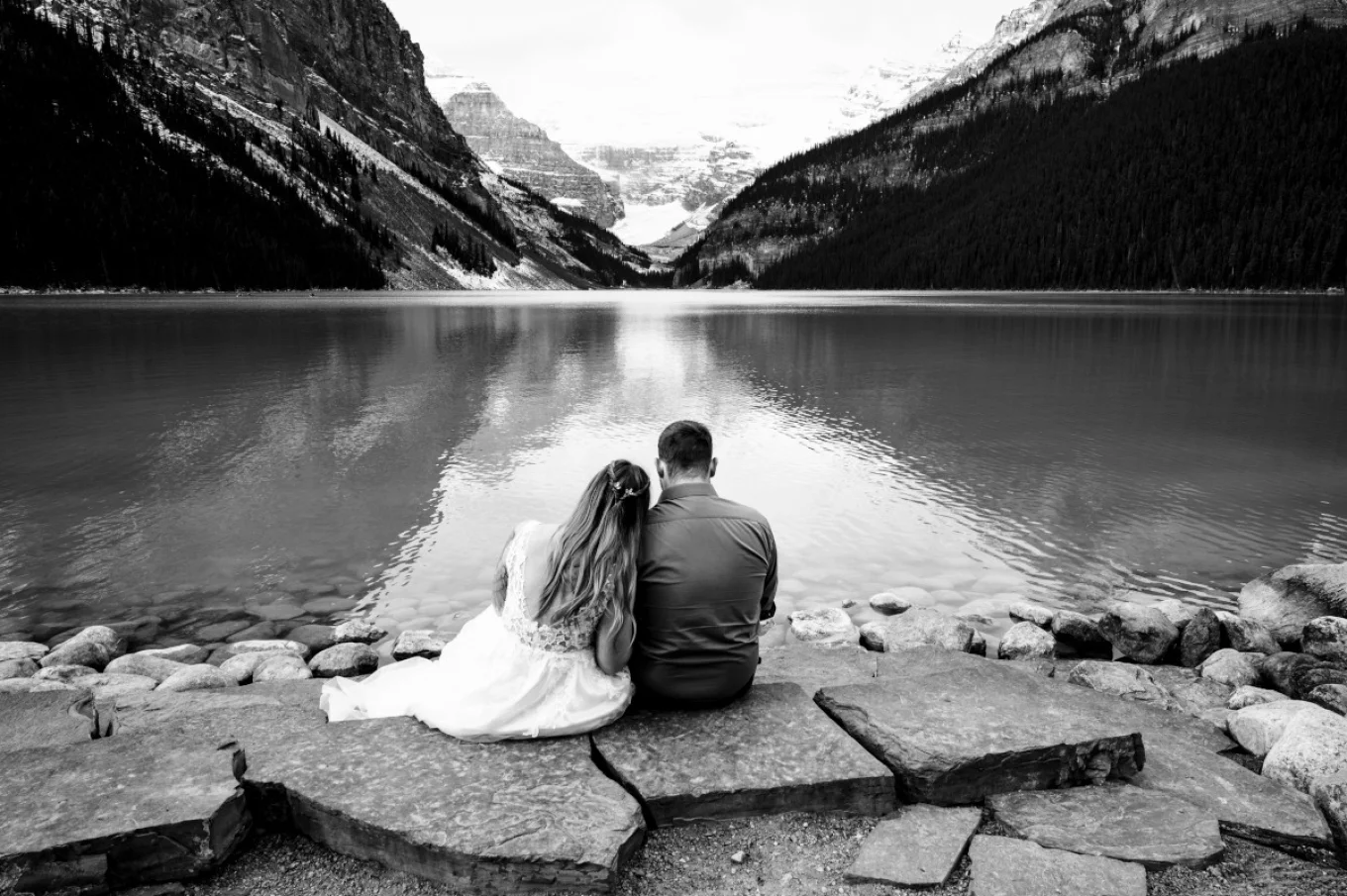 Groom and Bride sit at the stairs an enjoy unique Lake Louise in Banff.