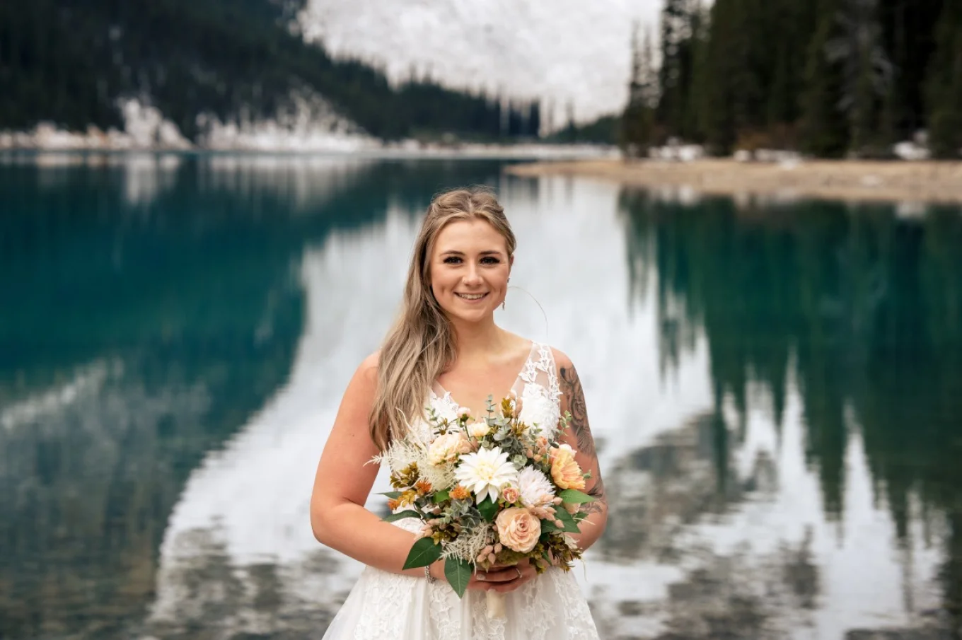 Bride's portrait at Moraine Lake in Banff. Bride holds colourful flowers.