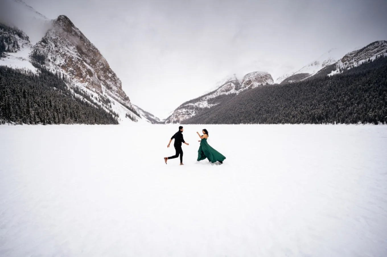 Couple dance in the middle of frozen Lake Louise. They are surrounded by gorgeous mountains.