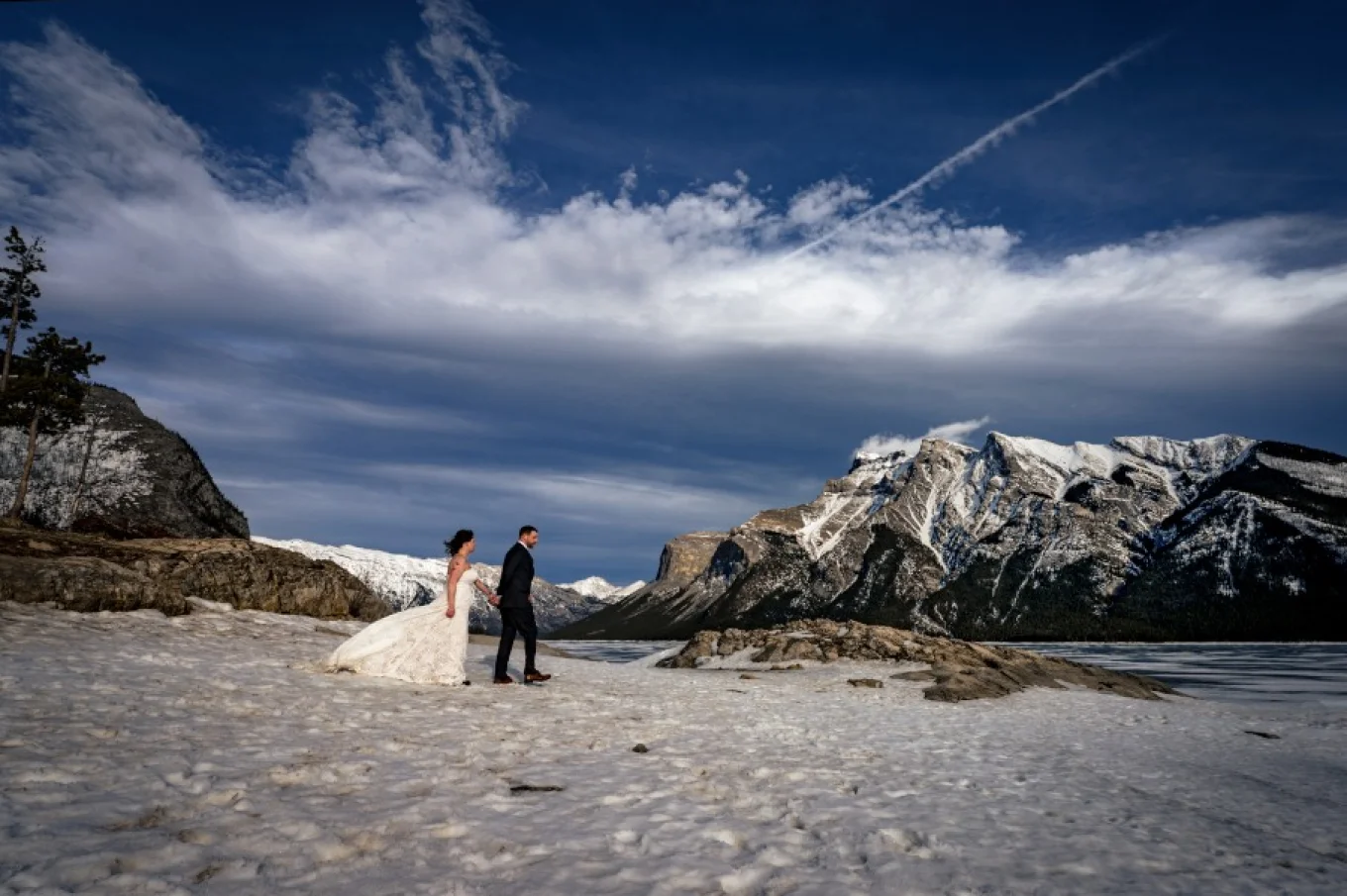Newlyweds walk down the Minnewanka Lake.