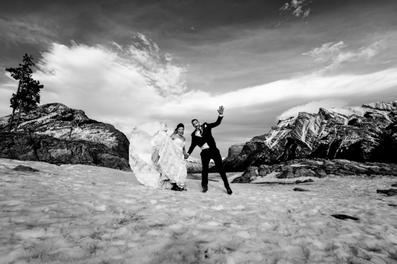 Groom and bride have hun during their photo session at Minnewanka Lake. They jump high and lough.