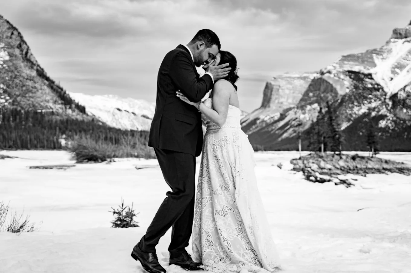 Black and white portrait in Banff National Park. Couple are kissing after their wedding.