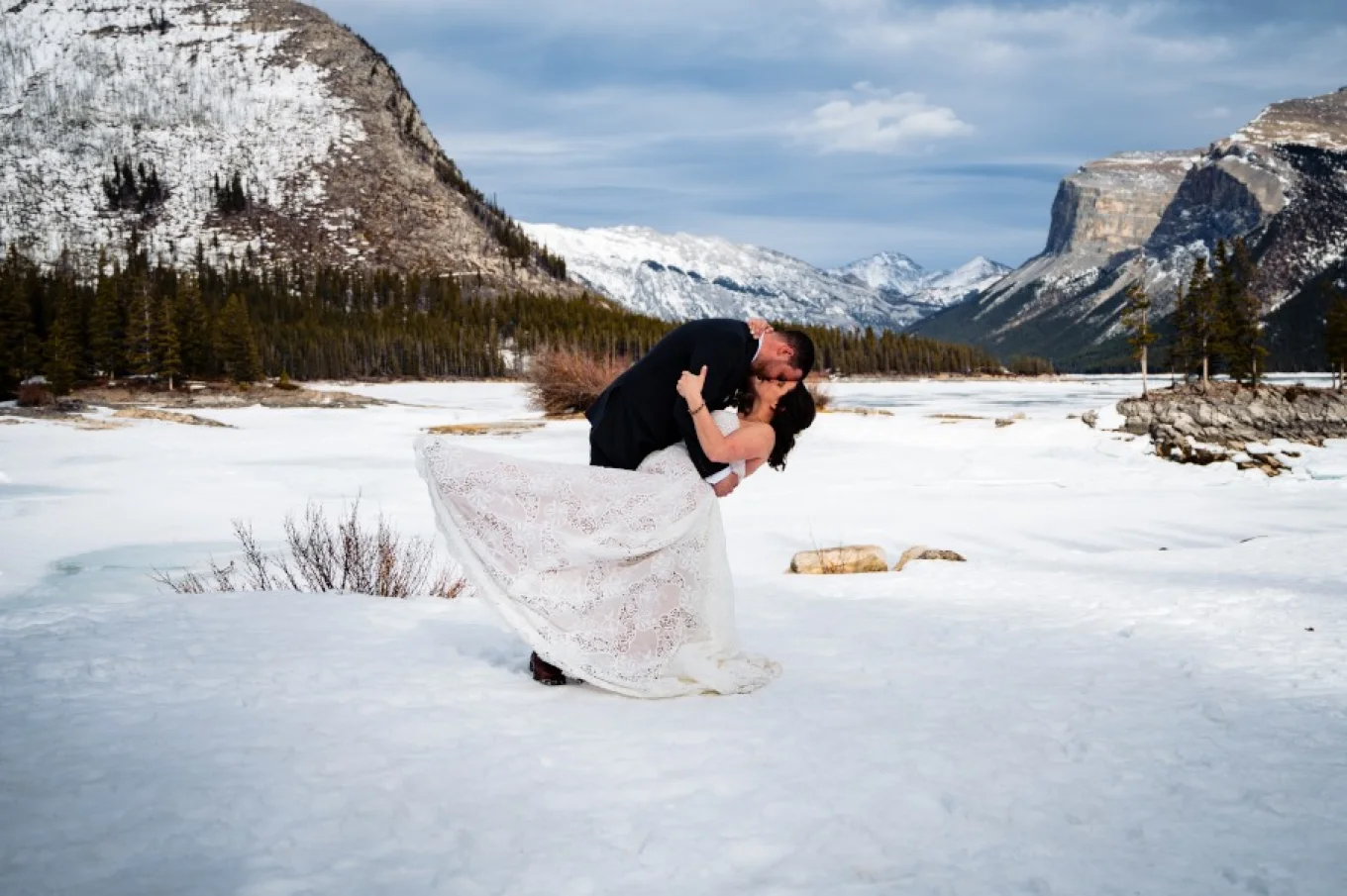 Newlyweds dance during winter wedding session in Banff. They are surrounded by the mountains.