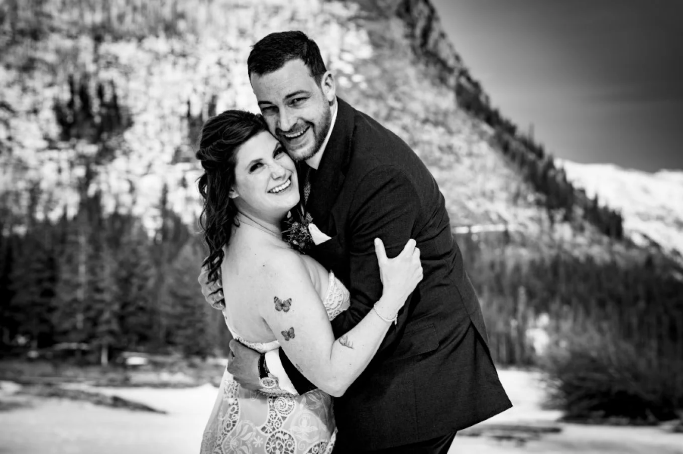 Bride and groom hug each other and smile to the camera.