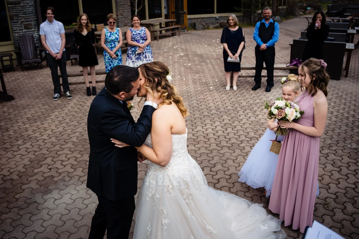 First kiss during elopement ceremony in Banff. Guests happy to see kissing couple.