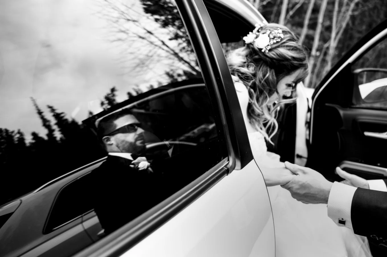 groom's reflection in the car window while he helps the bride go out from the wedding limo.