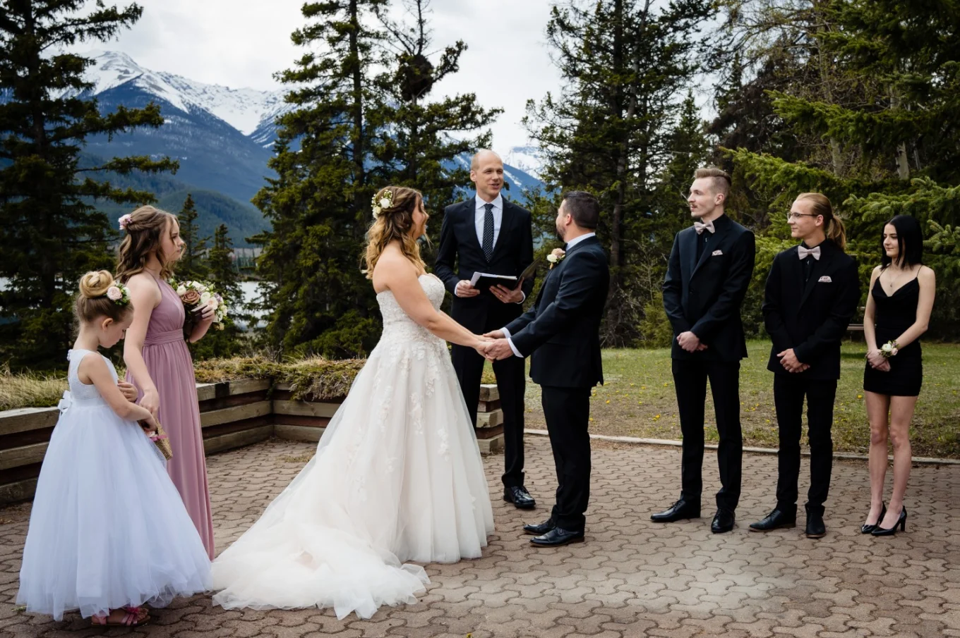Officiant gives speech during Banff Wedding Ceremony. Bride and groom hold hands.