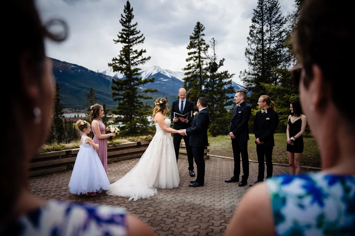 Banff Wedding Ceremony hold outside of Juniper hotel. Bride and groom look at each other while guests admire the ceremony.