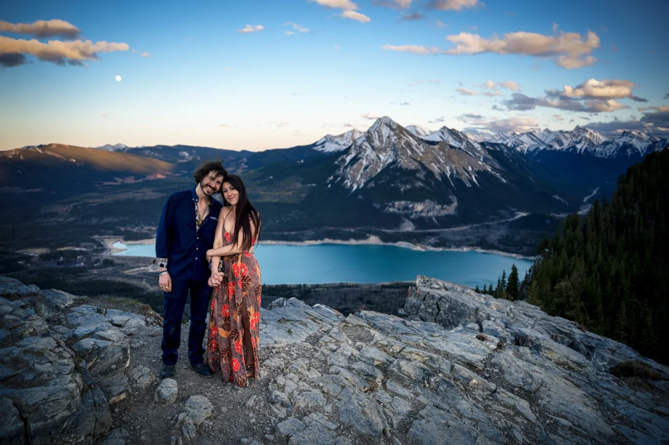 Banff Engagement Photography on the top of the mountain with a couple holding their hands and at Banff Wedding Photographer camera.