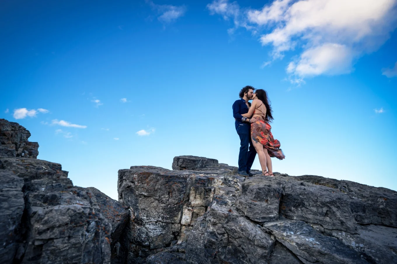 Banff Engagement Photographer created this unique photo of couple in love standing on giant rock in the Canadian Rocky Mountains.