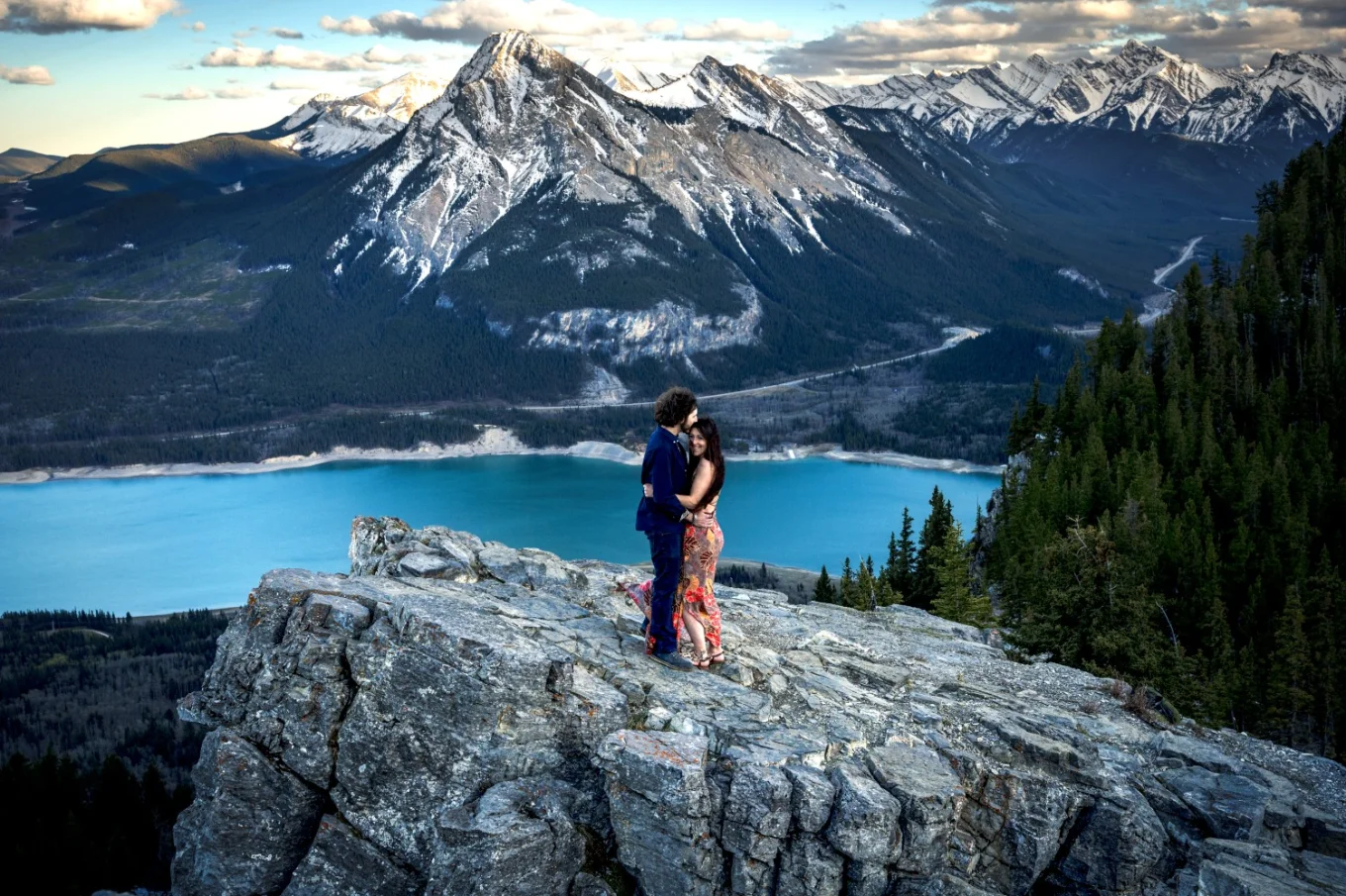 Couple in love huh each other on the top of the mountain against a background of giant mountains and blue lake.