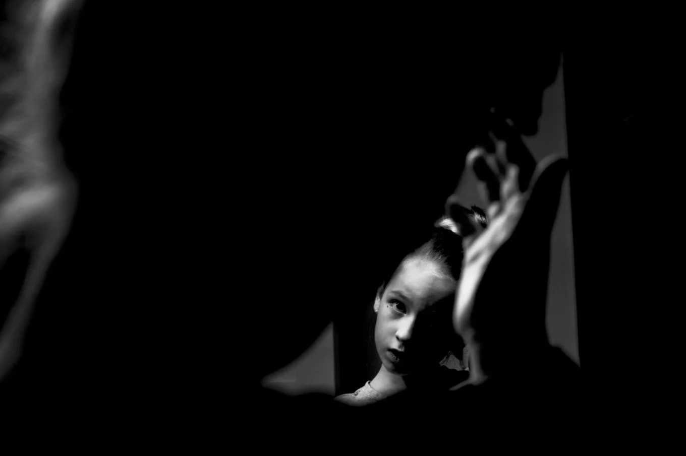 black and white photo of flower girl fixing her hair in the mirror