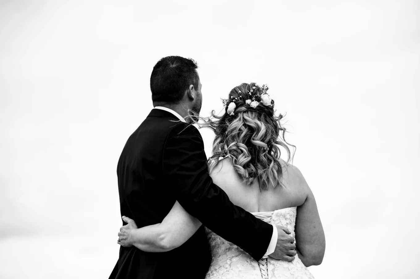 Bride and groom standing back to camera .