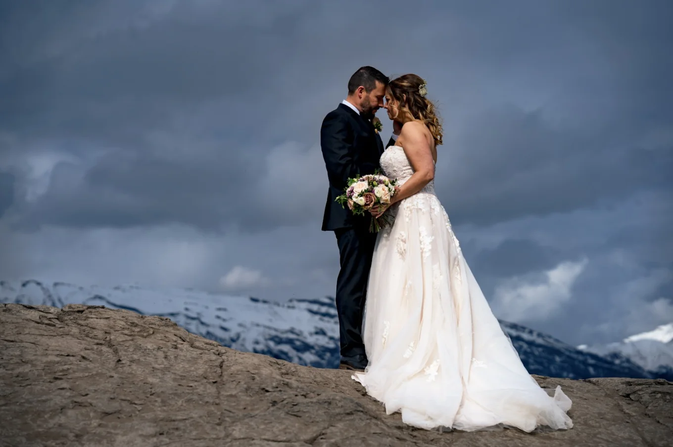 Bride and groom's portrait in the Canadian Mountains. They touches their foreheads.