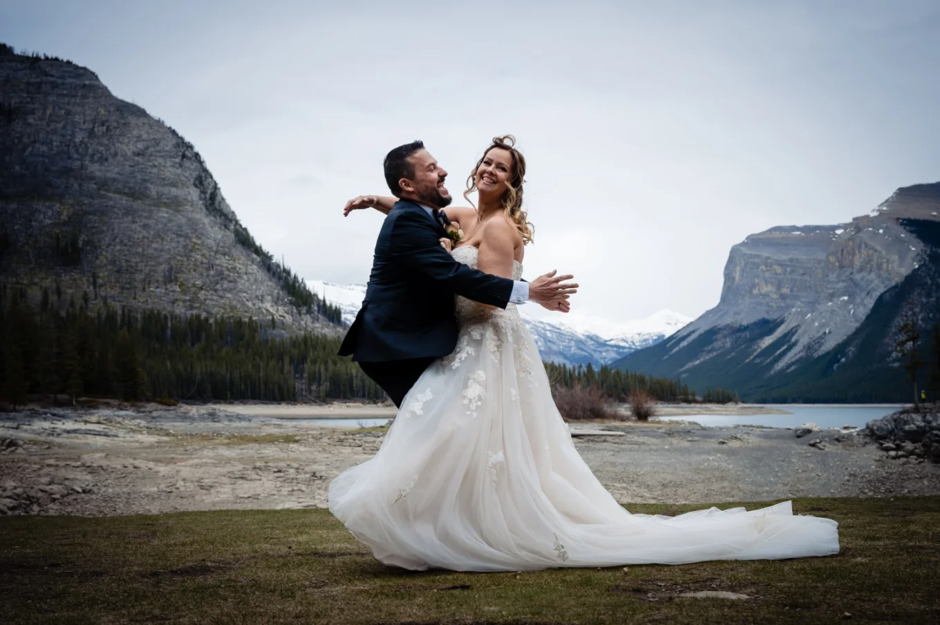 Newlyweds run into each other and hug at Minnewanka Lake in Banff.