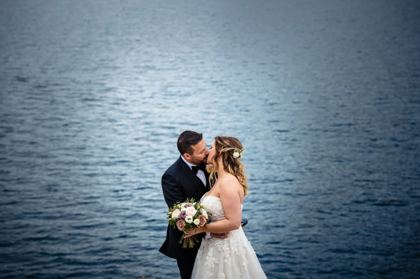 Bride and groom kiss at the lake in Banff.