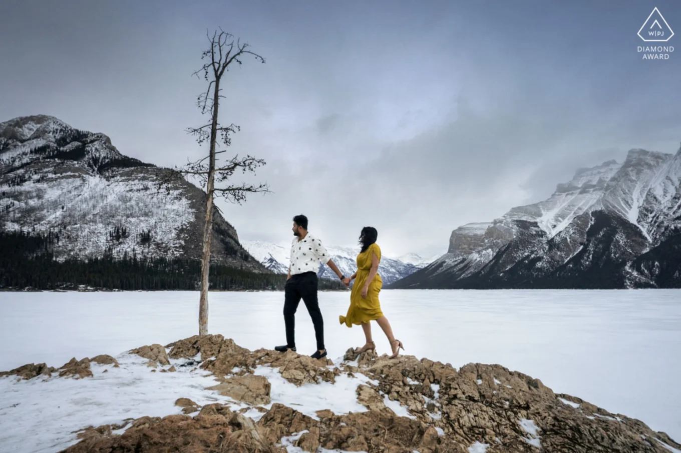 Engagement photo by the frozen Minnewanka Lake.