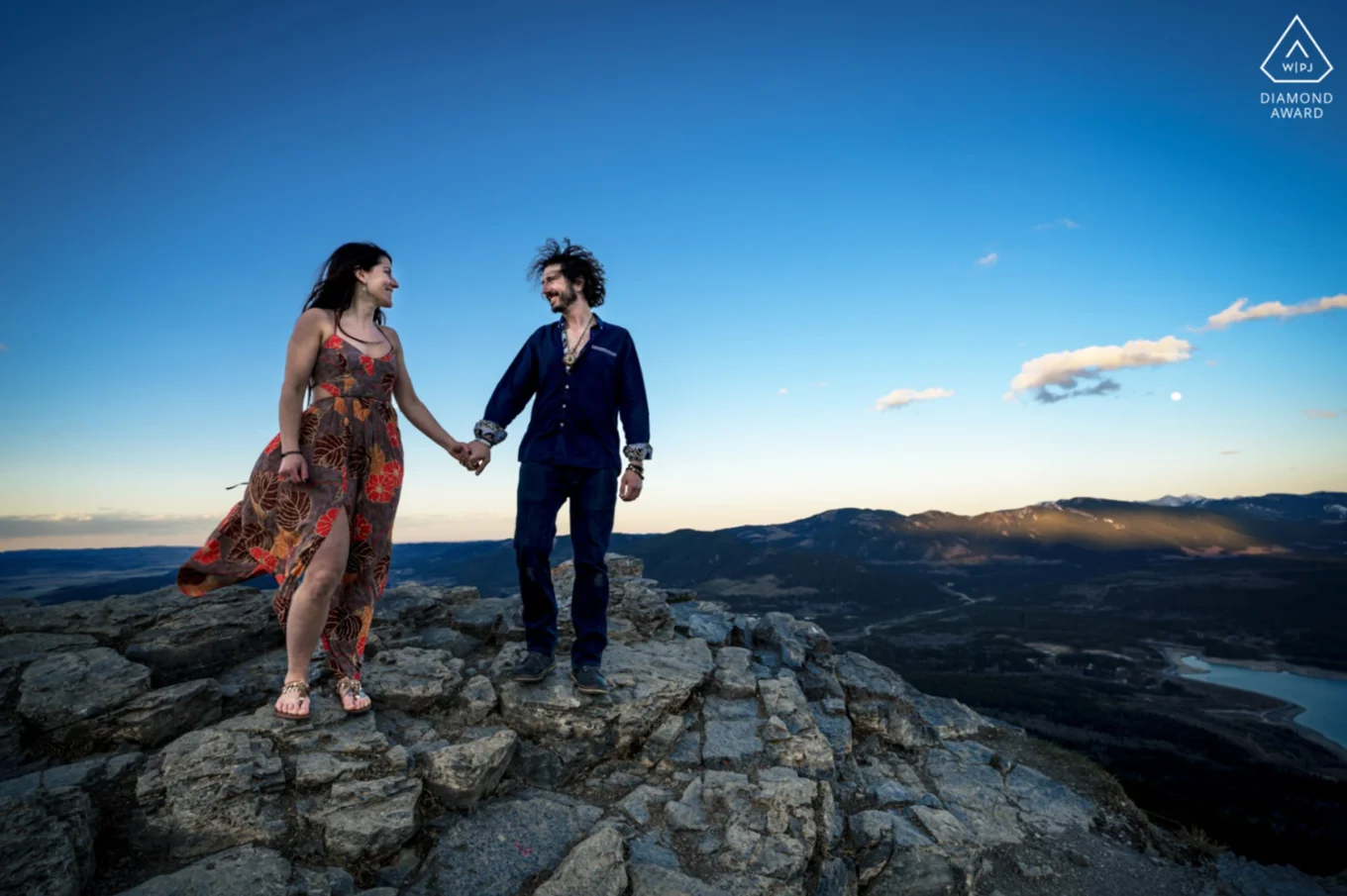 Engaged couple holds hands and look at each other during engagement session in Kananaskis Country Canada.