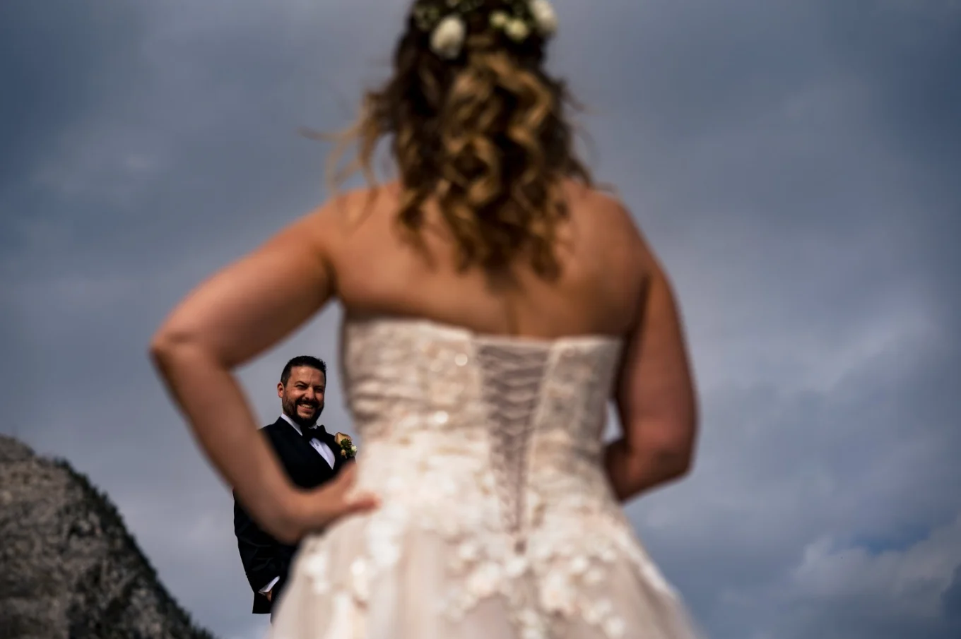 Groom look at the beautiful bride. His reaction captured through the bride's hand. Creative photography by Calgary Wedding Photographer.