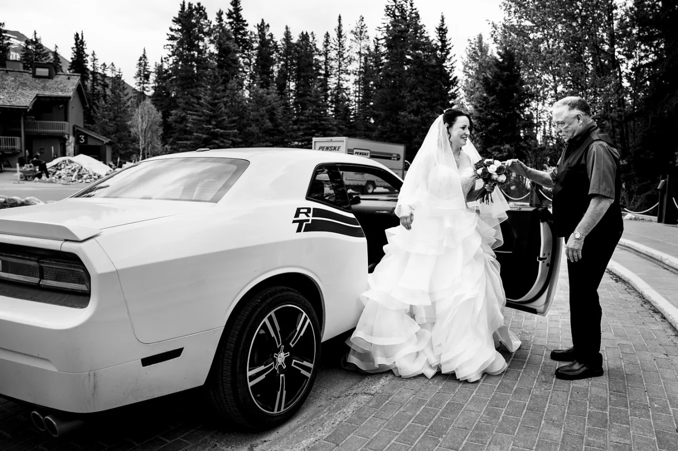 Bride is getting out from a white car to the wedding ceremon in Banff. Her dad helps her.