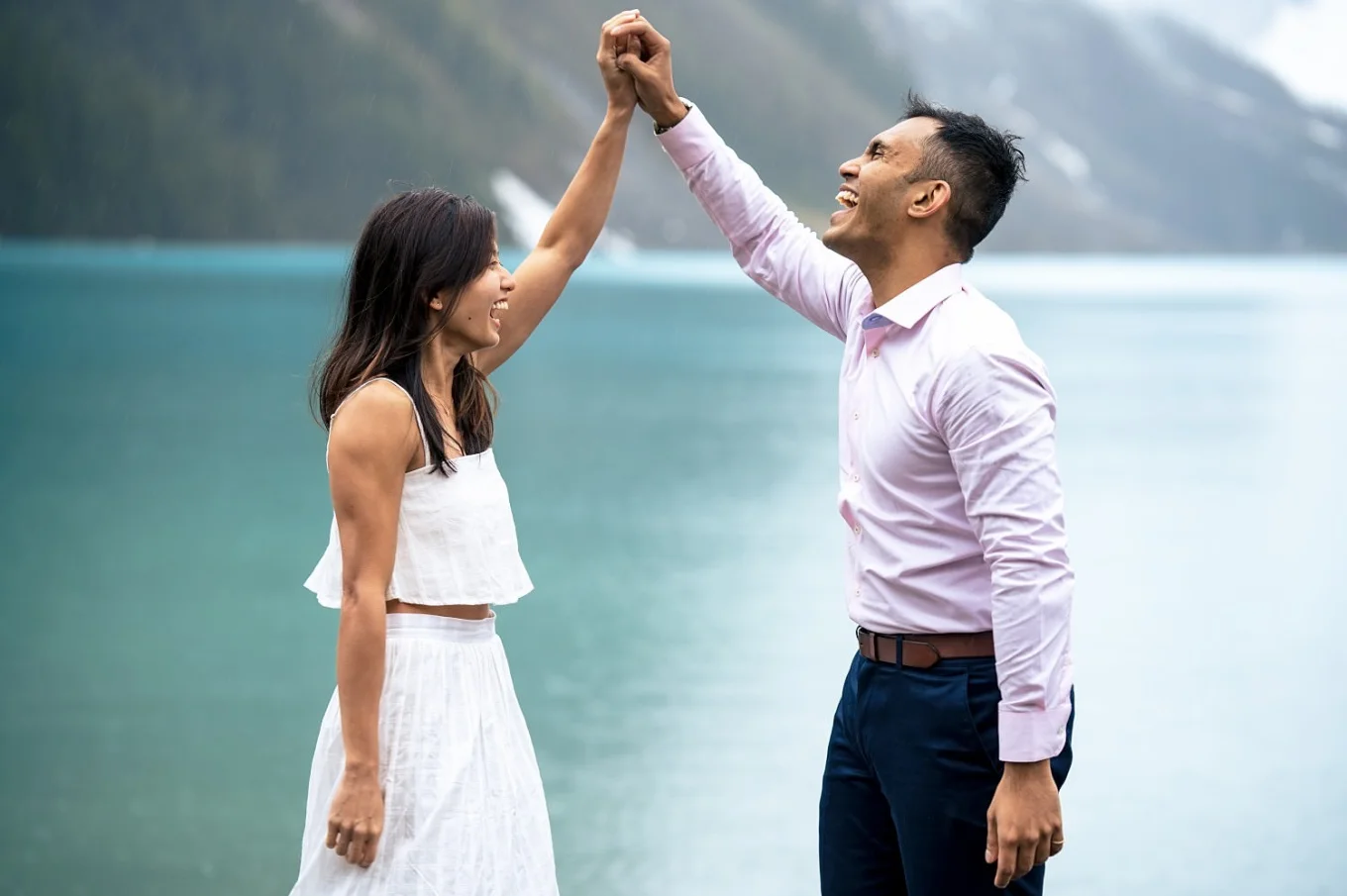 Couple in love hold theirs hang above heads and laugh.