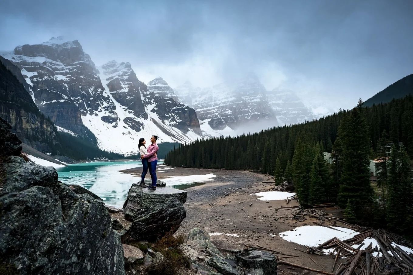 Amazing adventure engagement session at Moraine Lake showing a couple in love standing on a tremendous rock.