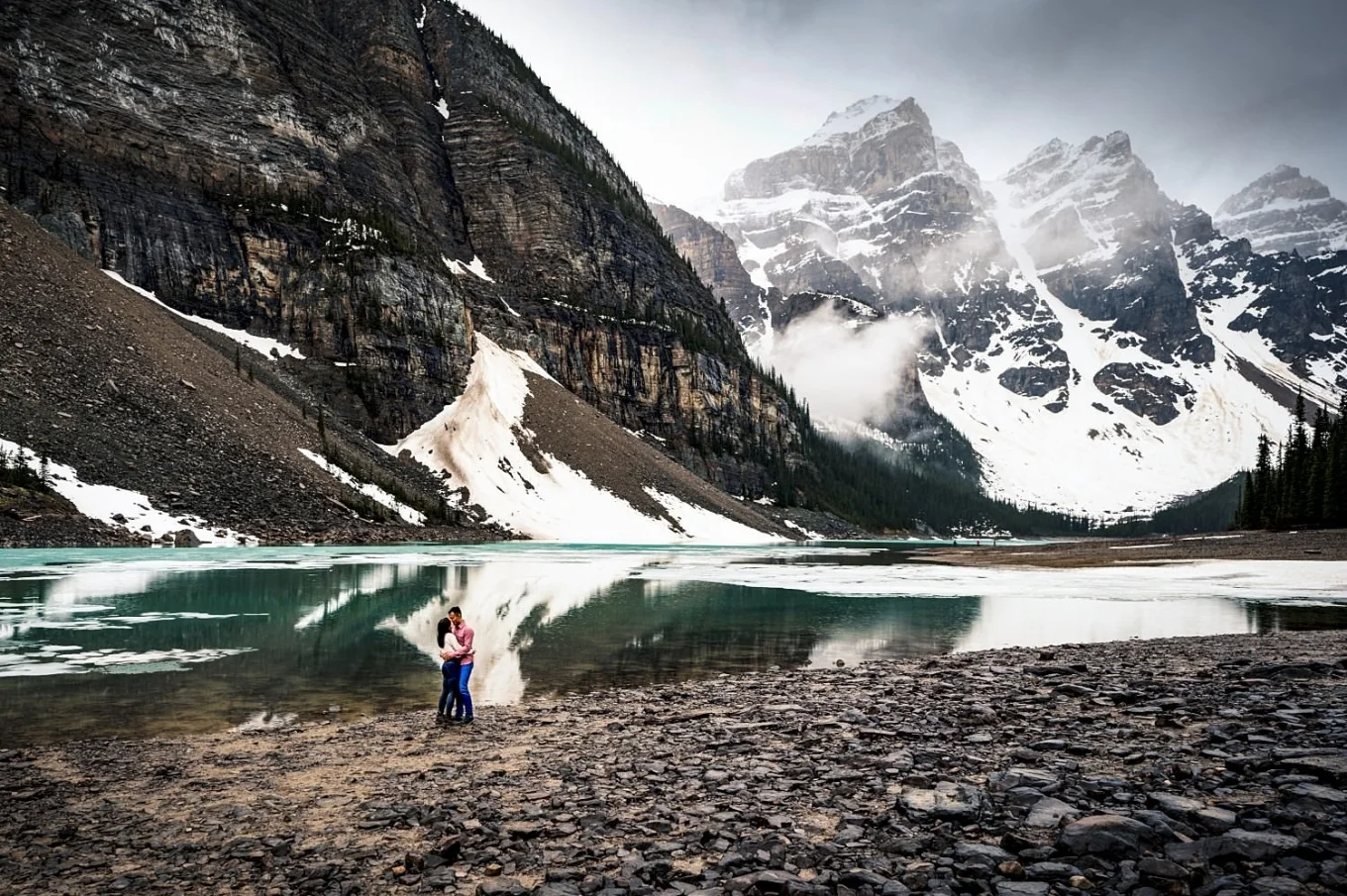 Amazing engagement portrait at Moraine Lake, on the background turquoise lake and snowy mountains.