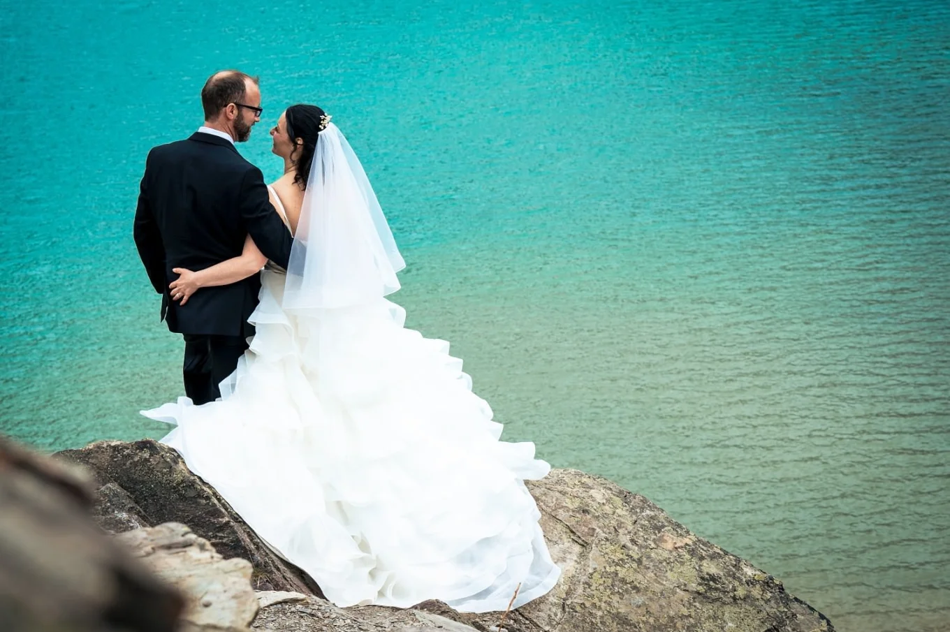 Bride grabs the grooms butt during wedding photo session by the lake