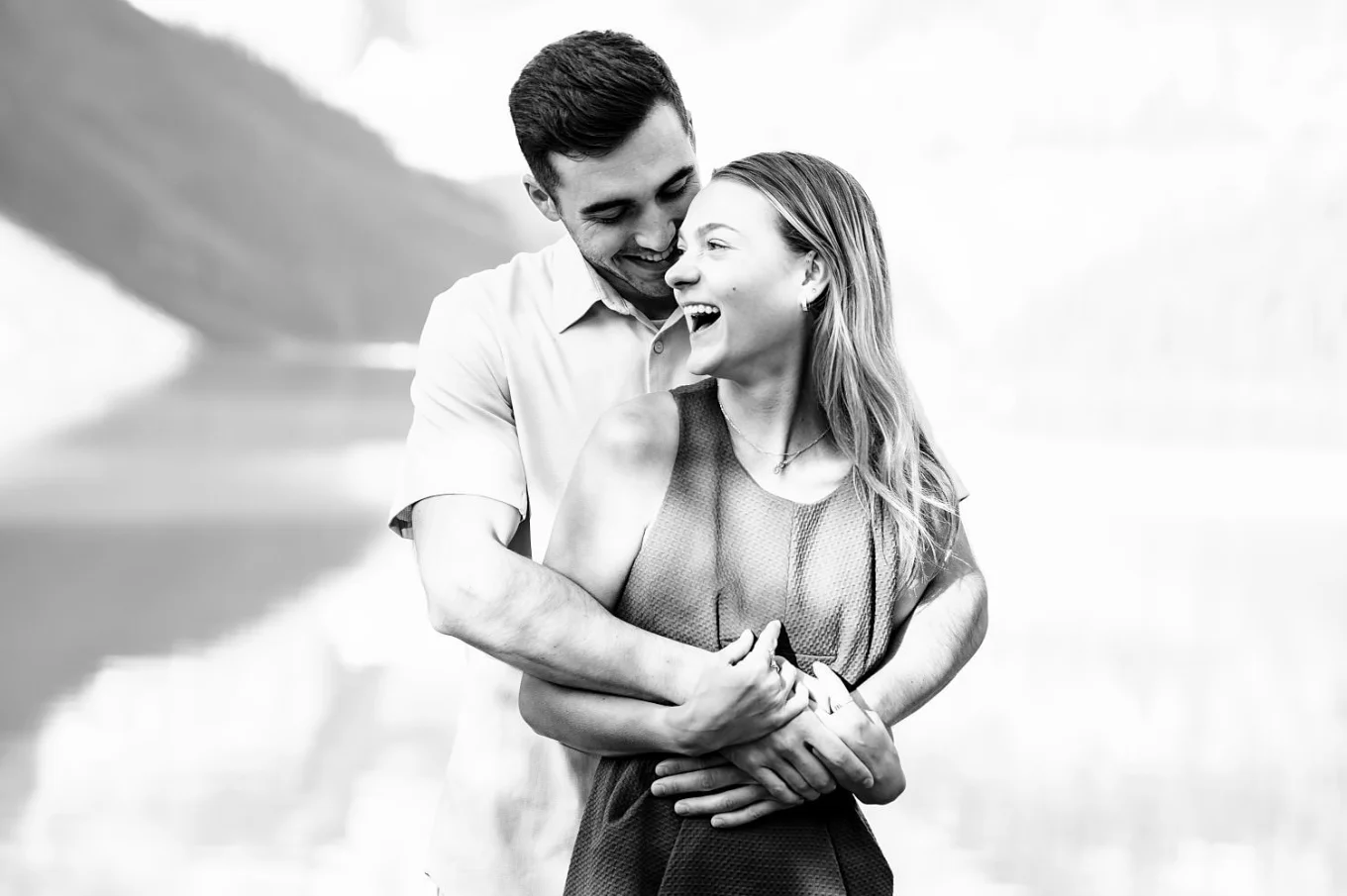 A man whispers his fiancee something to her ear . she loughs during this fun Banff Engagement Session with the best Wedding Photographer.