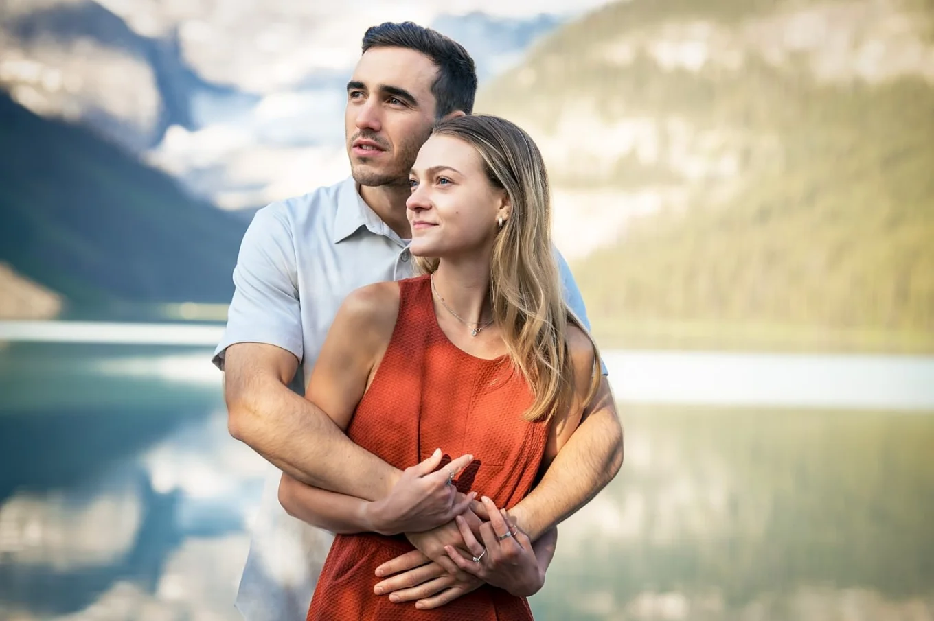Romantic engagement portrait of couple looking at the same direction and hugging.